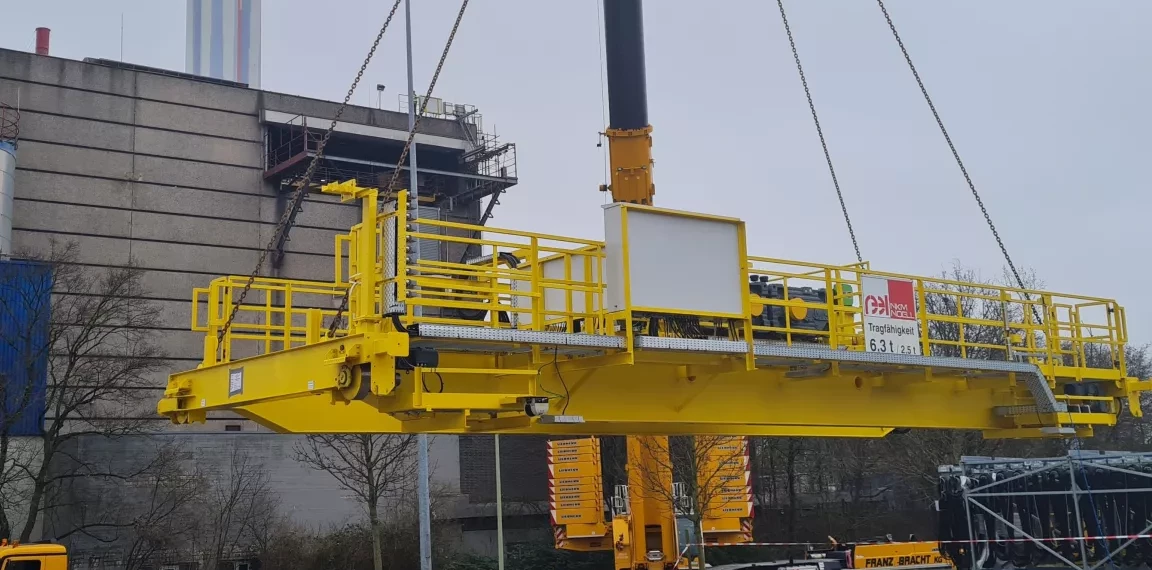 Ein Autokran hebt die neue Kranbrücke in den Müllbunker der Müllverbrennungsanlage